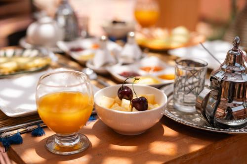 einen Tisch mit einer Schale Obst und einem Glas Orangensaft in der Unterkunft Riad Le Soleil de Bahia in Marrakesch