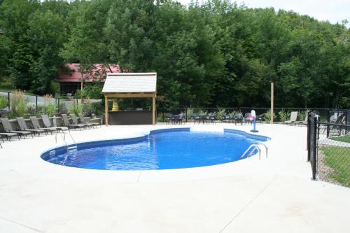a swimming pool with a gazebo in a yard at Auberge du Lac Morency in Saint-Hippolyte