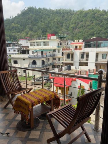 two chairs and a table on a balcony with buildings at The Little House in Rishīkesh