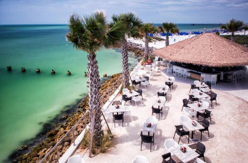 a restaurant on the beach with palm trees and the ocean at Opal Sands in Clearwater Beach