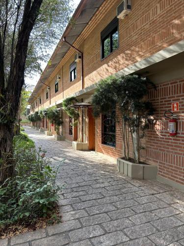 a brick building with potted trees next to a street at Hotel Villa D'Angelo in Itatiba