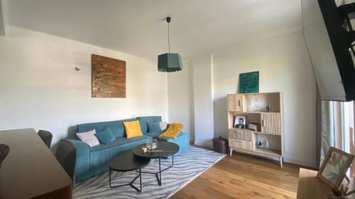 un salon avec un canapé bleu et une table dans l'établissement Confort et modernité Ajaccio, à Ajaccio