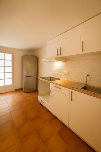 une cuisine avec des armoires blanches et un réfrigérateur en acier inoxydable dans l'établissement Le jardinet d'Emma - Appart RDC avec jacuzzi, parking, au calme, à Raphèle