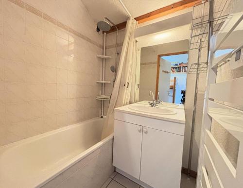 une salle de bain avec un lavabo, une baignoire et un miroir dans l'établissement Résidence Les Balcons Du Charvin - Au coeur de l'Espace Diamant, à côté de l'aire de loisirs et de l'arrêt de ski-bus MAE-3064, à Notre-Dame-de-Bellecombe