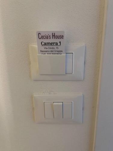 a white lightswitch on a wall with a sign on it at Cecia's House in Bassano del Grappa