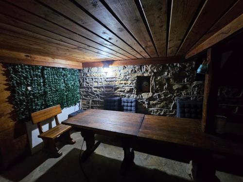 a room with a wooden table and a stone wall at Къща за гости Хитър Петър in Apriltsi