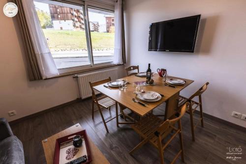 a dining room with a table with chairs and a television at Résidence Le Bois D'aurouze - Studio pour 4 Personnes MAE-8874 in Le Dévoluy