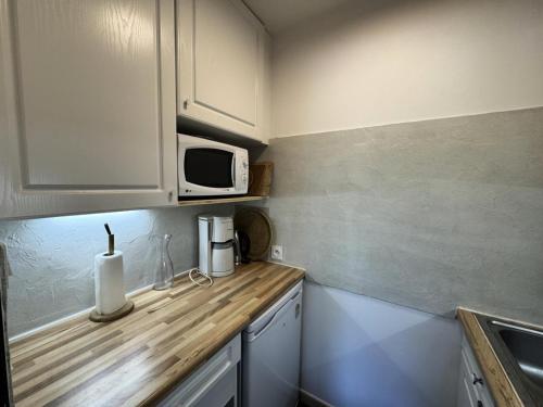 une cuisine avec un comptoir avec un micro-ondes dans l'établissement Résidence Les Melezes - Studio vue montagne · Accès pistes par navette · Parking extérieur MAE-0944, à Champcella