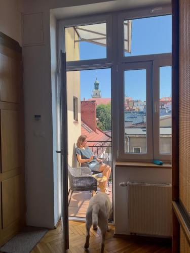 a woman sitting in a chair with a dog looking out the window at Apartament Ratuszowy in Cieszyn