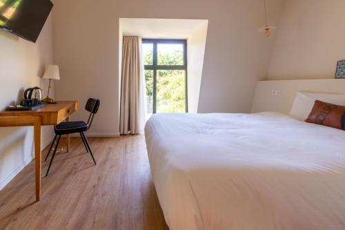 a bedroom with a bed and a desk and a window at Hôtel La Cachette de Nina- Madame rêve - Saint-Girons in Saint-Girons