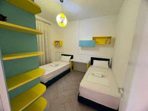 a small room with two beds and a shelf at Onis Apartment in Vlorë