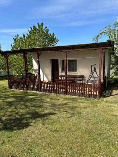a house with a porch with a wooden fence at Holiday - domek letniskowy in Charzykowy