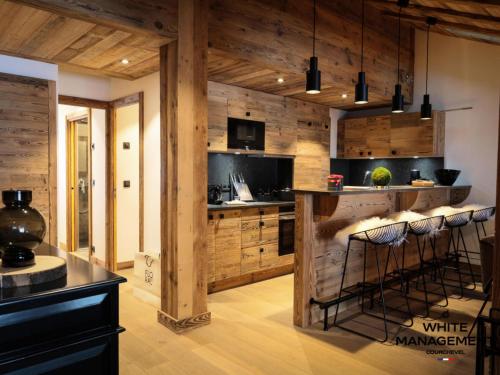 - une cuisine avec des murs en bois et un comptoir avec des tabourets de bar dans l'établissement Résidence Grandes Bosses - Beau penthouse au charme montagnard MAE-5844, à Courchevel
