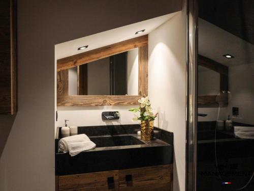 une salle de bain avec un lavabo et un miroir dans l'établissement Résidence Grandes Bosses - Beau penthouse au charme montagnard MAE-5844, à Courchevel