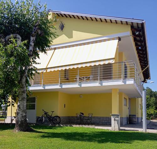 a yellow house with a balcony and a tree at Villa Gemma in Alba