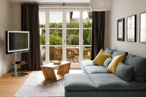 ein Wohnzimmer mit einem blauen Sofa und einem TV in der Unterkunft Alpenhof Garnihotel & Ferienwohnungen in Garmisch-Partenkirchen