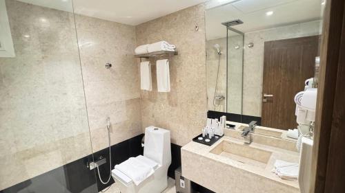 a bathroom with a toilet and a sink and a mirror at Golden Season Hotel - Al-Rass - فندق جولدن سيزون - الرس in Al Rass
