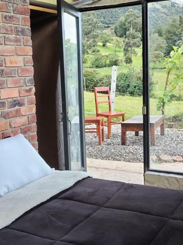 a bedroom with a bed and a patio with a chair at Casa Quinta Mozart in Guatavita