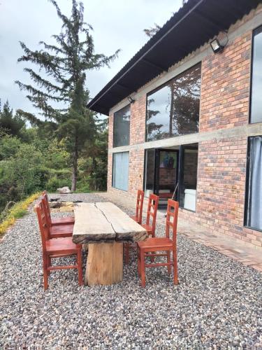 a wooden table and chairs in front of a house at Casa Quinta Mozart in Guatavita