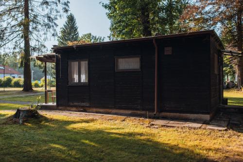 a small black cabin in a field with trees at Rekreační a školicí středisko Zájezek in Chlum u Třeboně