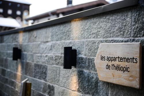 a sign on the side of a brick wall at Appartements de l'Héliopic in Chamonix-Mont-Blanc