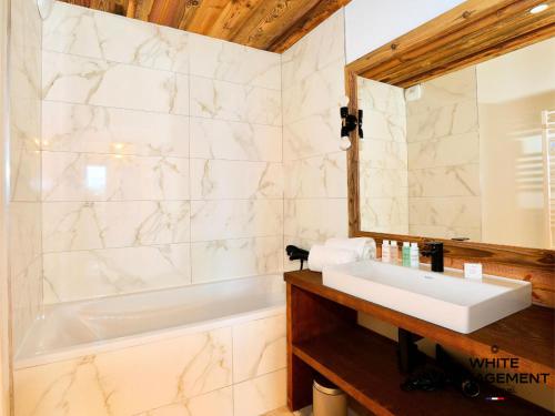 une salle de bain avec une baignoire, un lavabo et un miroir dans l'établissement Résidence Ariondaz Heliantheme - Superbe 3 pièces cabine proche des pistes MAE-4824, à Courchevel