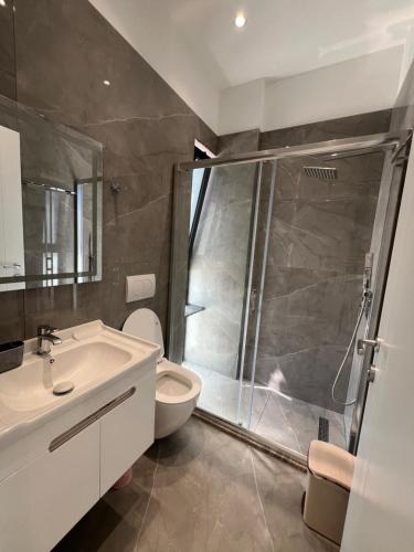 a bathroom with a shower and a toilet and a sink at Niks apartments in Vlorë