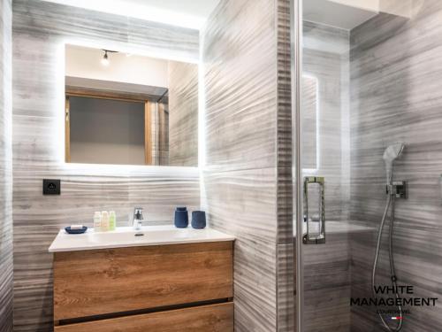 une salle de bain avec un lavabo et un miroir dans l'établissement Résidence Ariondaz Campanule - Superbe appartement familial MAE-8354, à Courchevel