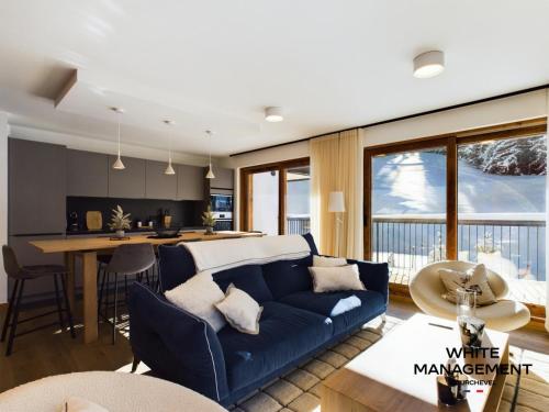 un salon avec un canapé bleu et une cuisine dans l'établissement Résidence Ariondaz Hellebore - Superbe appartement haut de gamme et ski-in MAE-4714, à Courchevel