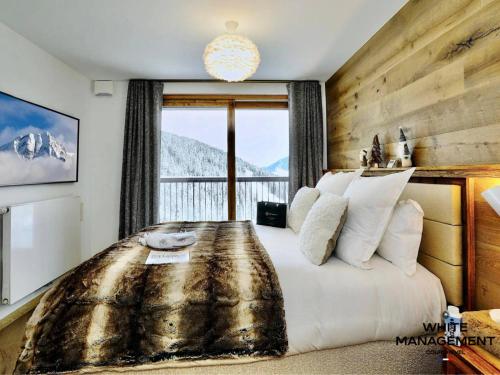une chambre avec un grand lit avec une grande fenêtre dans l'établissement Résidence Ariondaz Hellebore - Superbe appartement haut de gamme et ski-in MAE-4714, à Courchevel