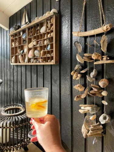 a person holding a glass of wine in a room with shells at Summerhouse With Hot Tub On Langeland in Tranekær