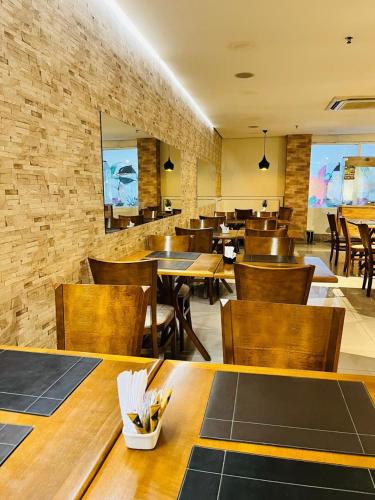 a restaurant with wooden tables and chairs and a brick wall at Blue Tree Premium Manaus in Manaus