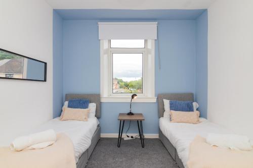two beds in a room with a window at Modern And Vibrantly Designed Apartment in Motherwell