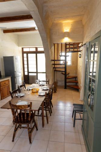 a dining room with a table and wooden chairs at Tal-Masklu farmhouse in Għarb