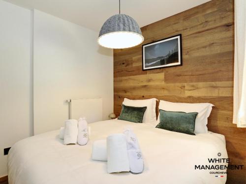 - une chambre avec un grand lit blanc et un mur en bois dans l'établissement Résidence Ariondaz Hellebore - Beau T2 Cabine pour 5 personnes MAE-7724, à Courchevel