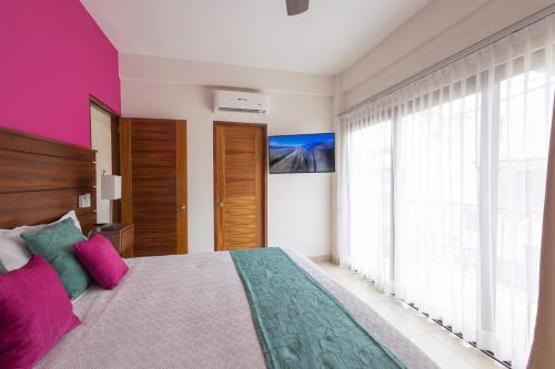 ein Schlafzimmer mit einem großen Bett mit rosa und grünen Kissen in der Unterkunft Beautiful view in Gringo Gulch 202 in Puerto Vallarta