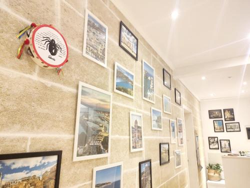 a wall of pictures on a wall with a clock at B&B Suites Via del Mare in Presicce