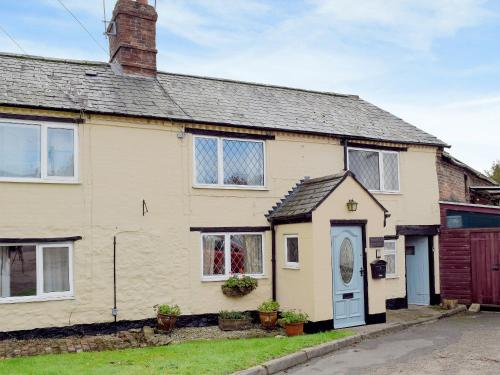 a yellow house with a blue door on a street at Rebecca's Cottage in Ashby Saint Ledgers