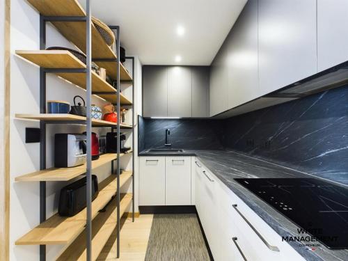 - une cuisine avec des placards blancs et des étagères en bois dans l'établissement Résidence Ariondaz Heliantheme - Appartement pour 6 personnes exposé Sud MAE-8931, à Courchevel