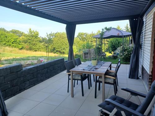 a patio with a wooden table and chairs and an umbrella at Ferienwohnung am Sendberg in Frielendorf