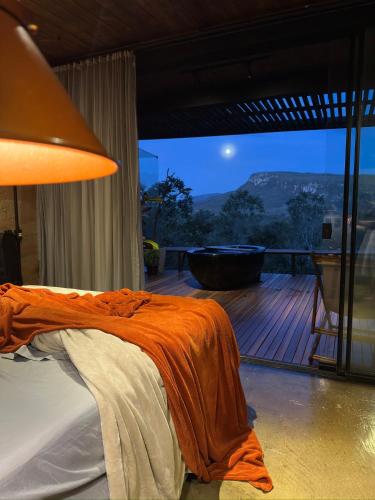a bedroom with a bed and a deck with a tub at A nossa casa da arvore in Cavalcante