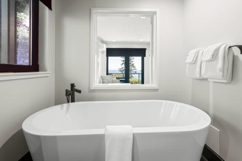 a white bath tub in a bathroom with a window at Black Rock Oceanfront Resort in Ucluelet