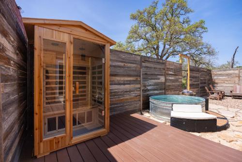 a wooden building with a hot tub next to a fence at Romantic Luxury stay w Sauna, Pool & Amenities on 10 acres in Wimberley