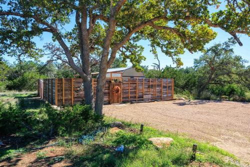 a wooden fence in a field with a tree at Romantic Luxury stay w Sauna, Pool & Amenities on 10 acres in Wimberley