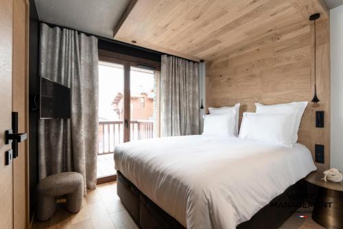 une chambre avec un grand lit blanc et une fenêtre dans l'établissement Résidence Les Glaciers - Chaleureux chalet contemporain à Courchevel 1650 MAE-4431, à Courchevel