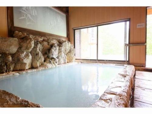 a large swimming pool in a room with a stone wall at Ebisuya - Vacation STAY 31583v in Hirayu