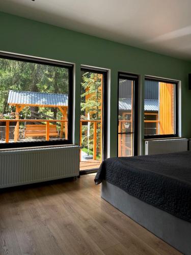 a bedroom with green walls and a bed and large windows at Savanna Mountain forest resort in Yablunytsya
