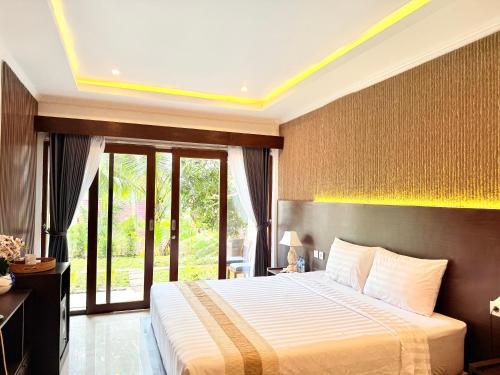 a bedroom with a large bed and a large window at Kelingking Tropical in batumadeg