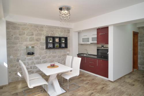 een keuken en eetkamer met een witte tafel en stoelen bij Apartments Risan in Risan