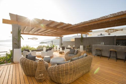 a patio with wicker chairs and tables on a wooden deck at Seaside apartments in Alikí